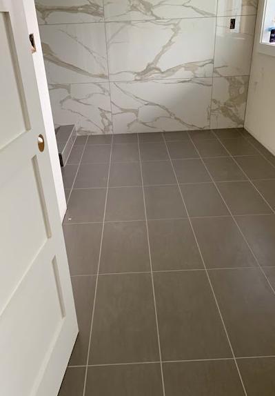 Empty tiled bathroom with marble-look wall and open door