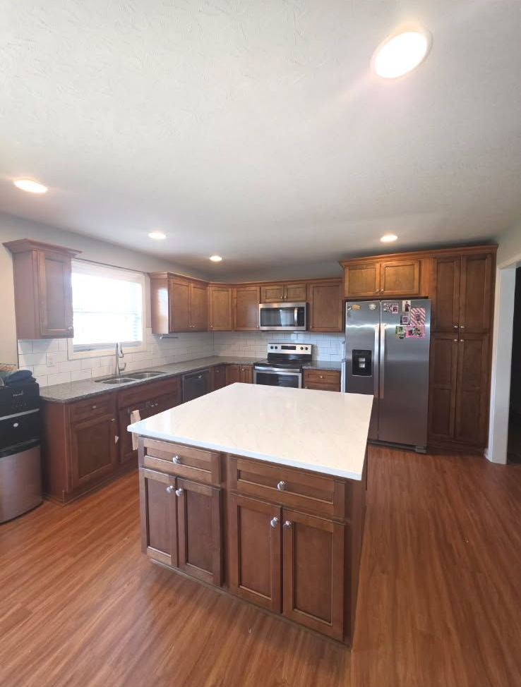 Kitchen with wooden cabinets, white countertops, and a stainless steel refrigerator.