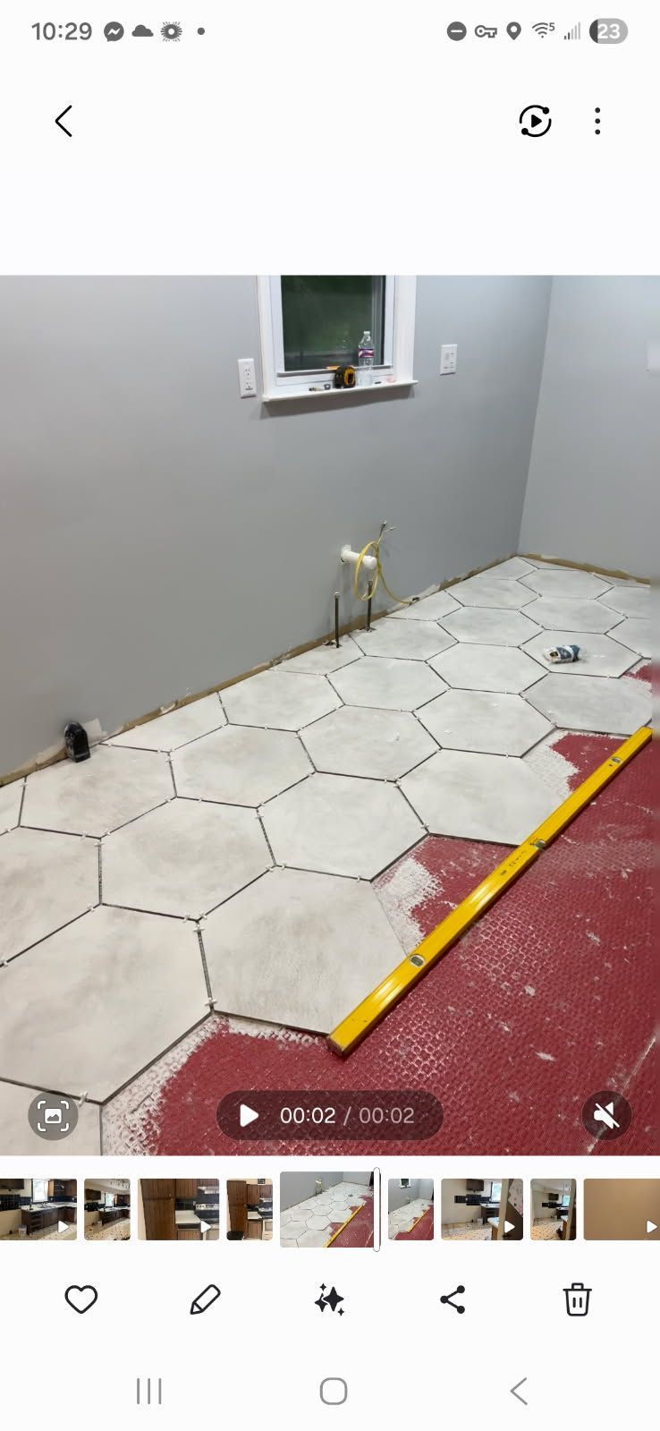 Small tiled room with gray walls, a window, and a yellow-red threshold strip near the floor.
