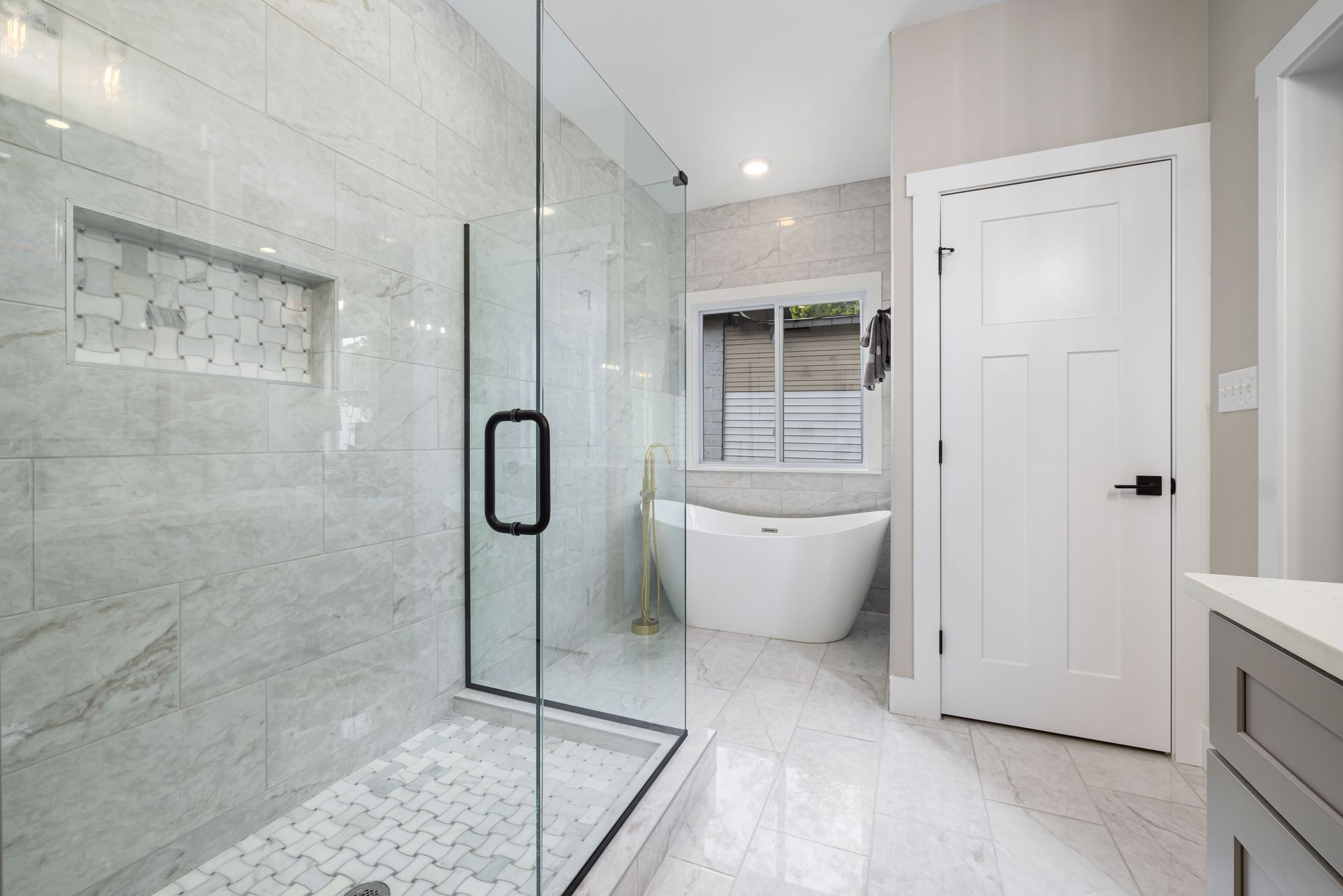 Modern white bathroom with glass shower, freestanding tub, and double vanity