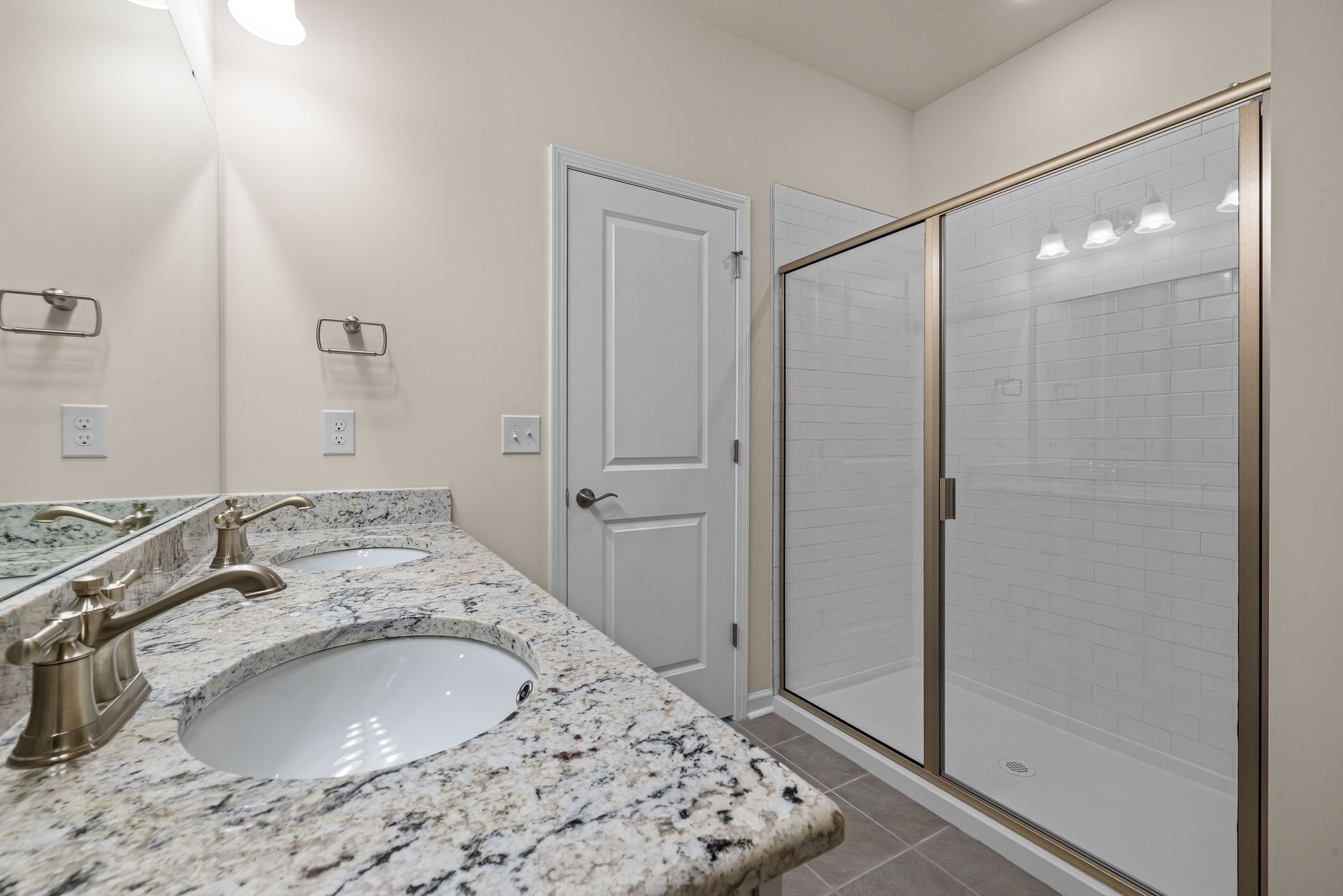 Bathroom with granite vanity, oval sink, and glass-enclosed shower with white tile.