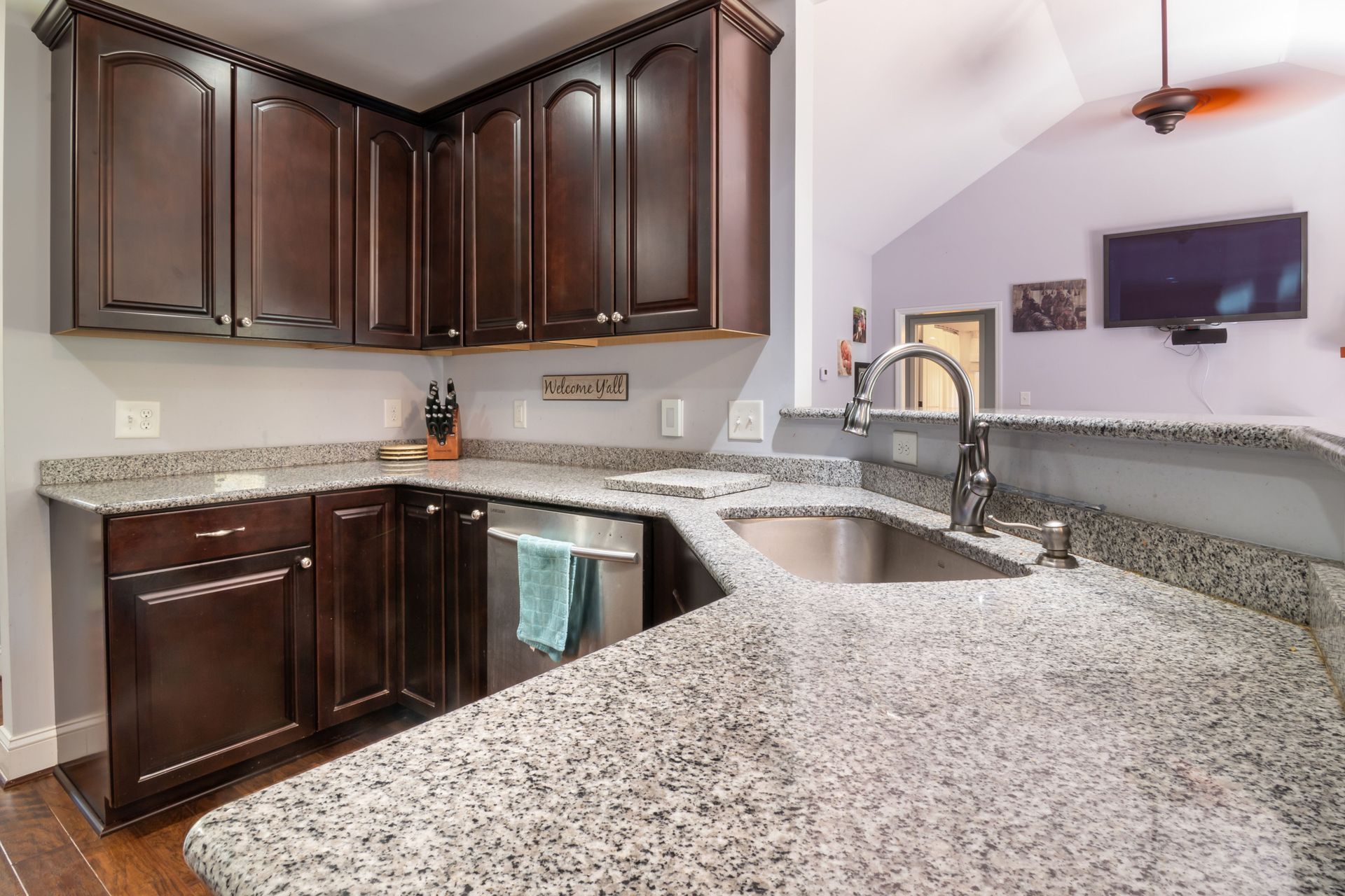 Modern kitchen with dark wood cabinets, granite countertops, and stainless steel sink