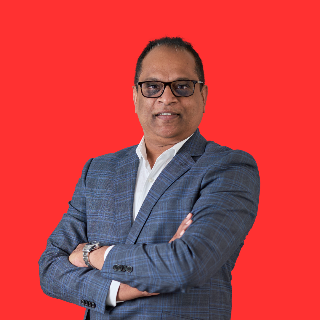 A man in a suit and glasses is standing with his arms crossed.