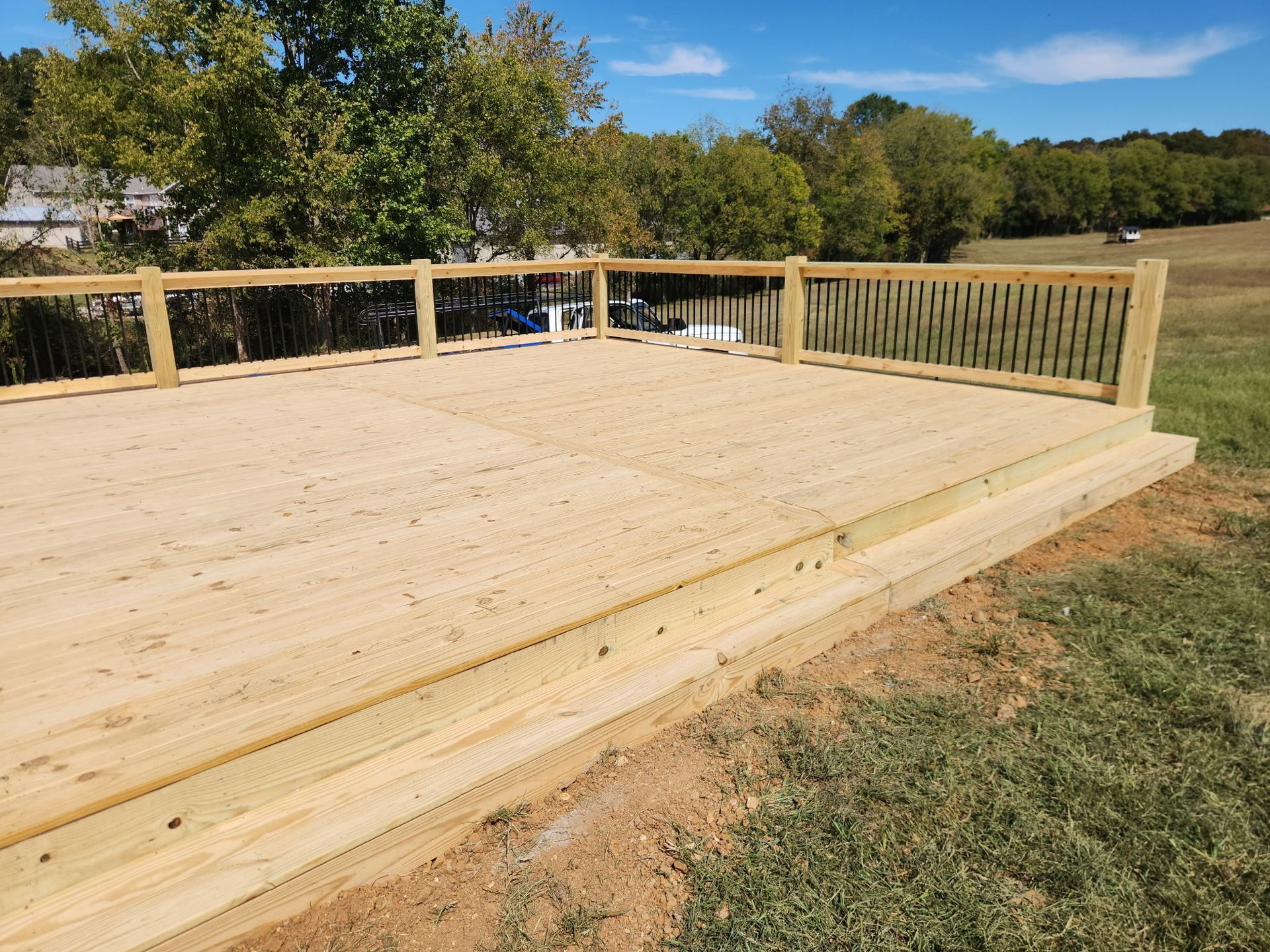 New wooden deck with railings overlooking a grassy yard and trees
