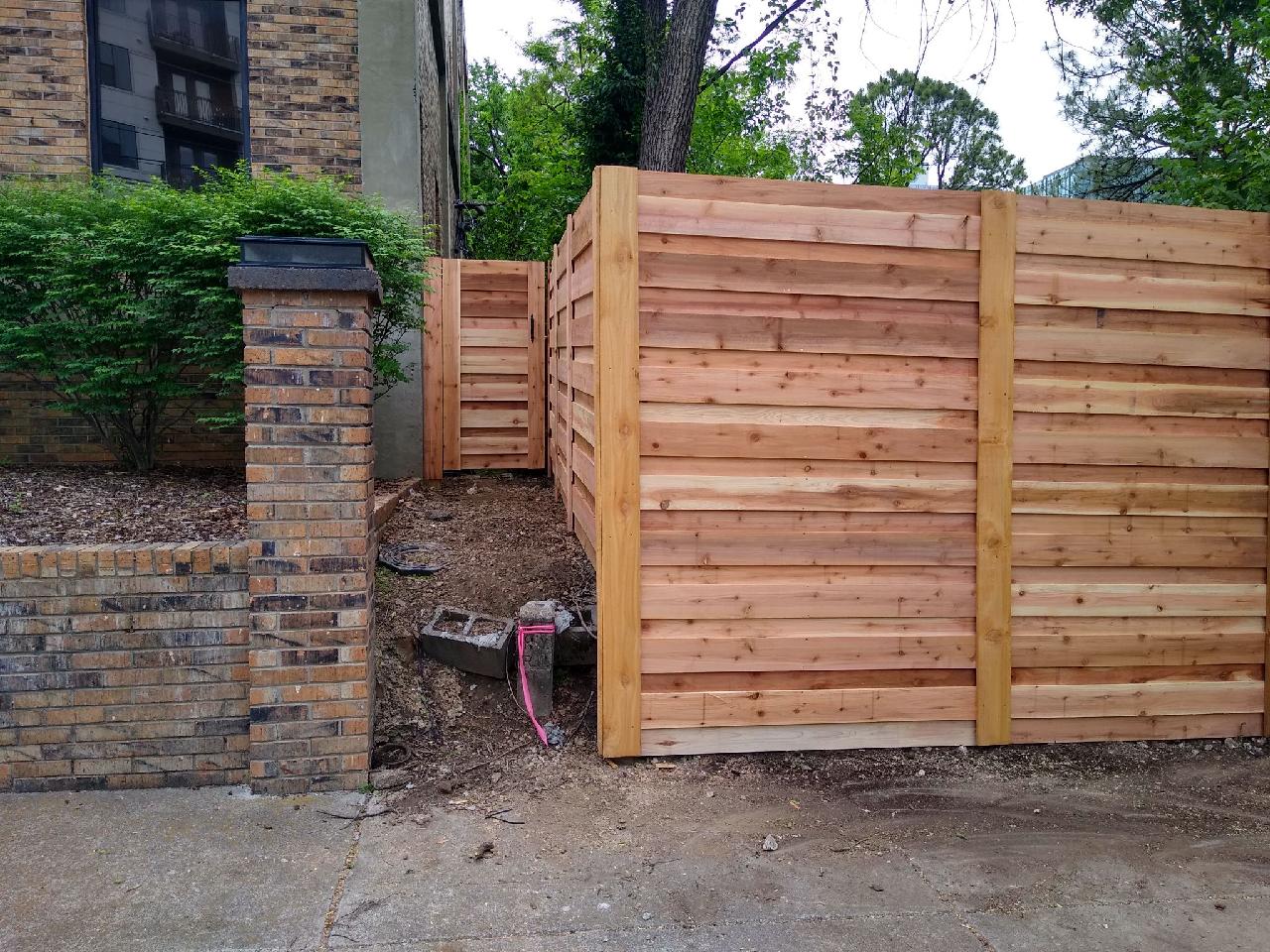 A wooden fence is in front of a brick building
