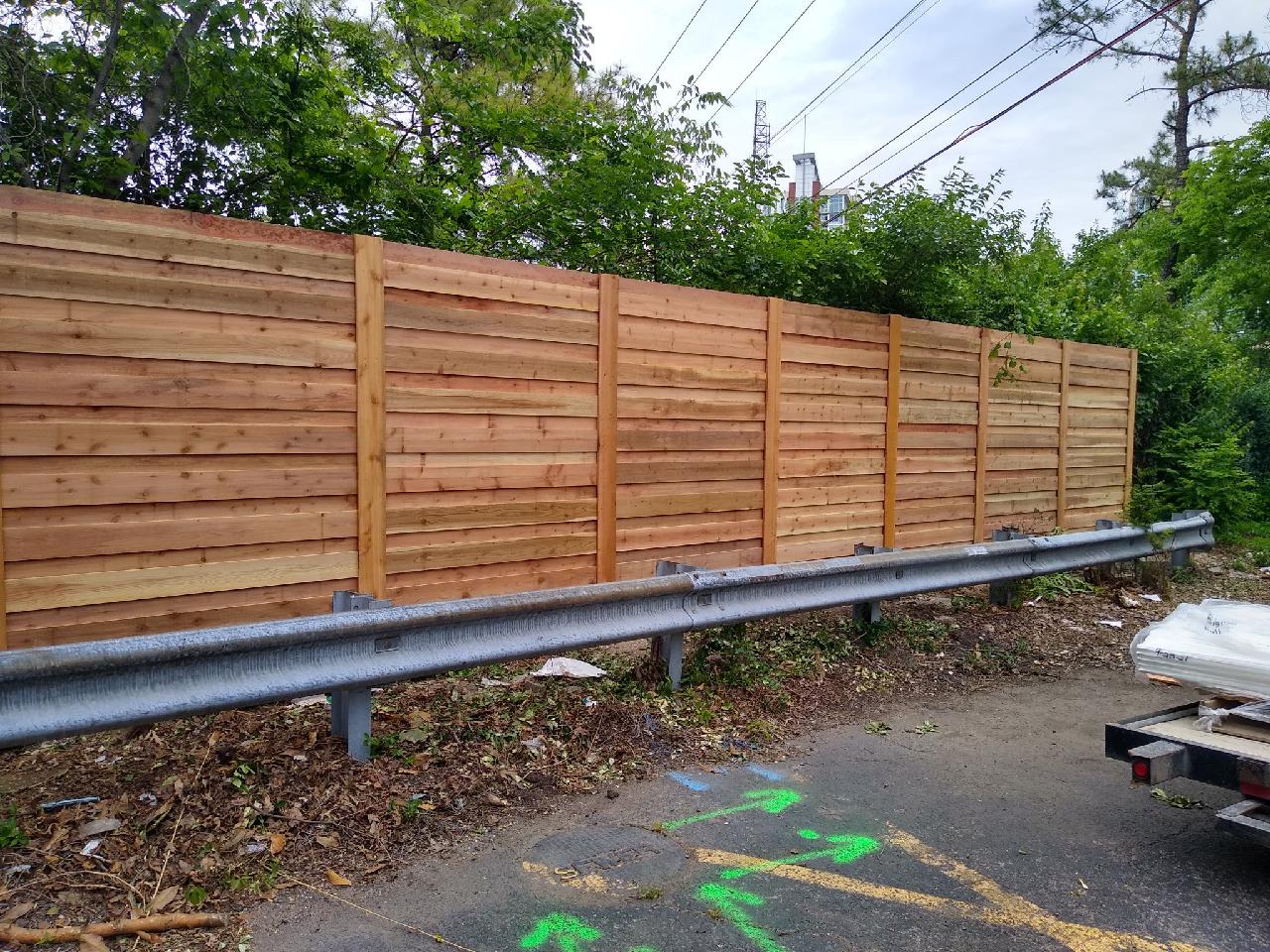 A wooden fence is sitting on the side of a road next to a highway.