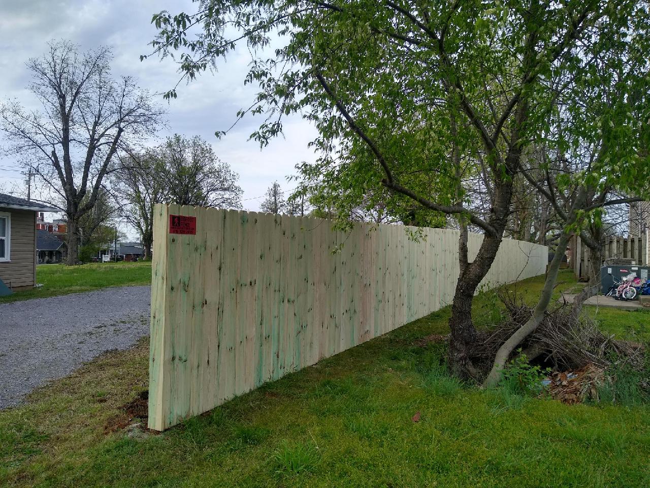 A wooden fence is surrounded by grass and trees in a yard.