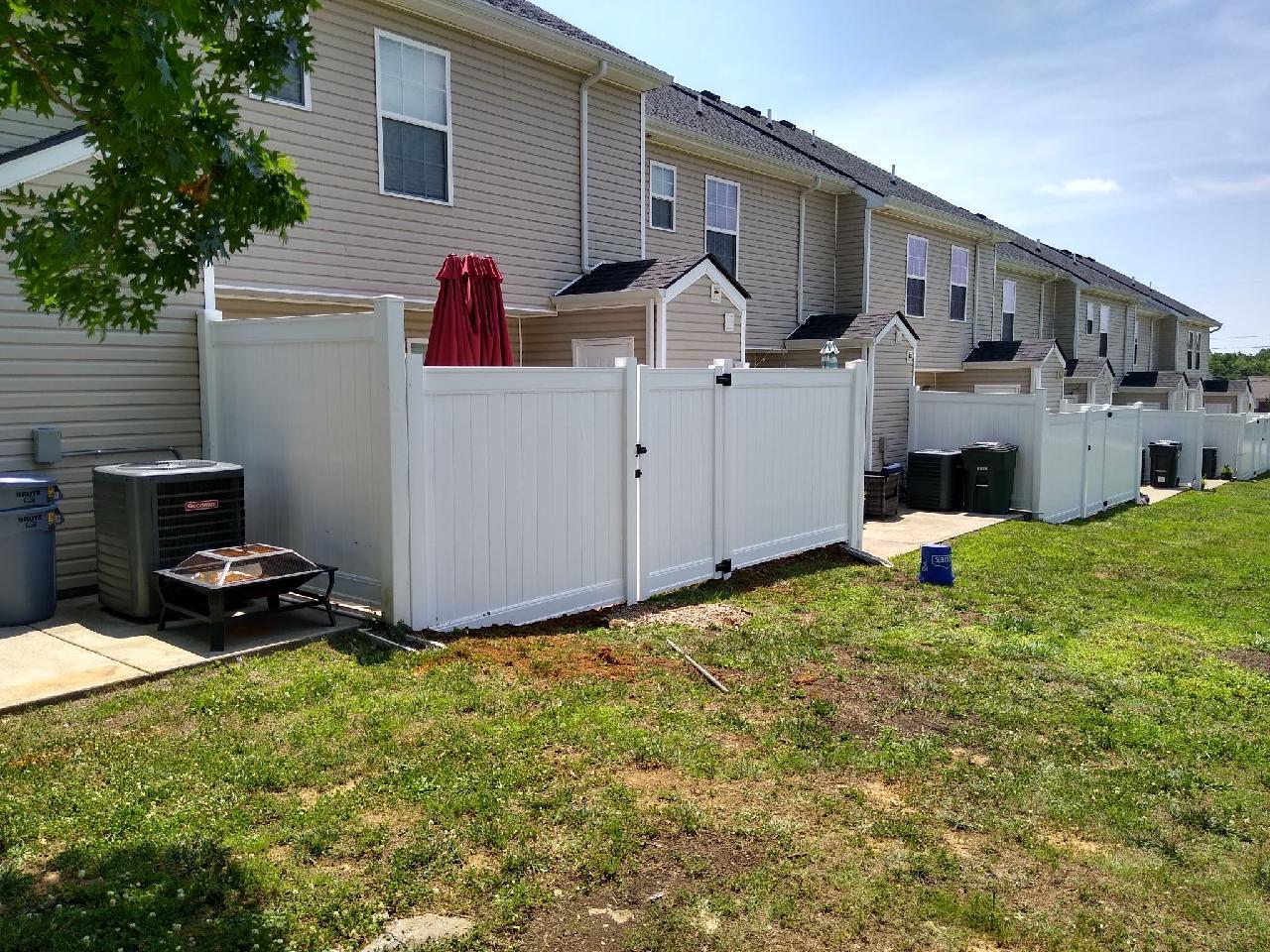 There is a white fence in the backyard of a house.