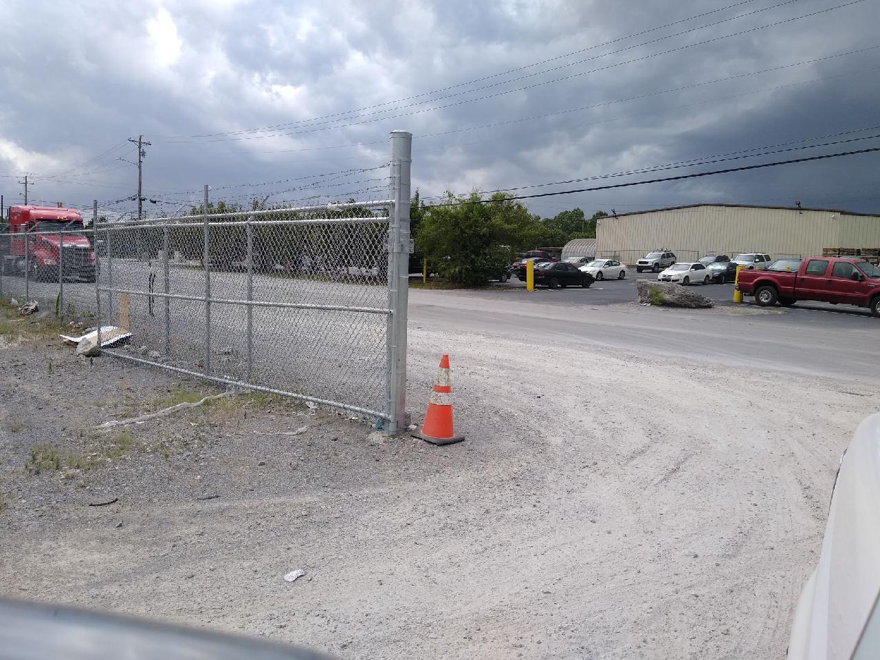 A chain link fence surrounds a parking lot with a red truck in the background.