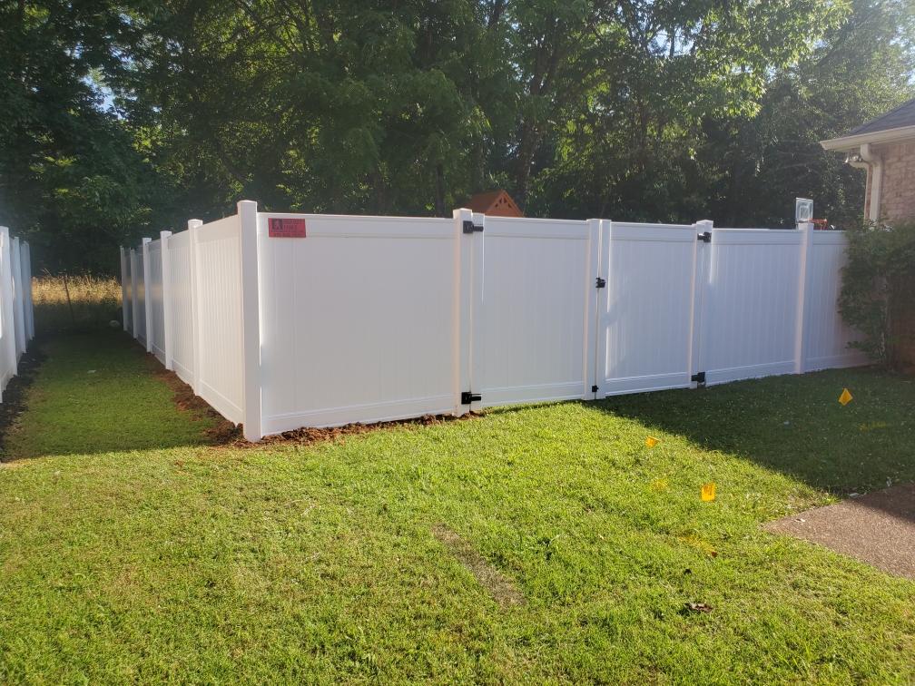 A white fence is sitting in the middle of a lush green yard.