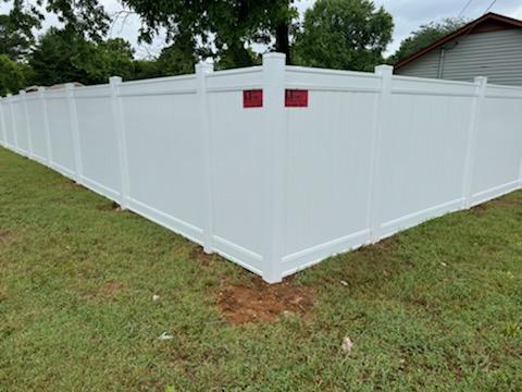 A white fence is sitting in the middle of a lush green field.