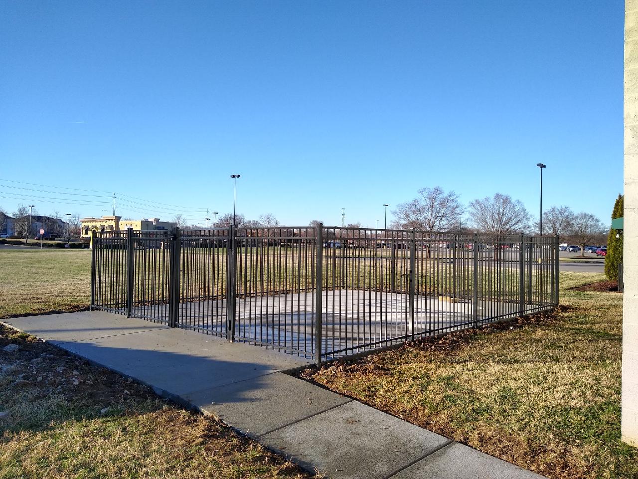 A fence surrounds a concrete walkway in a park.