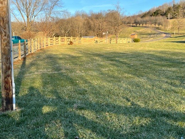 A large grassy field with a wooden fence in the background.