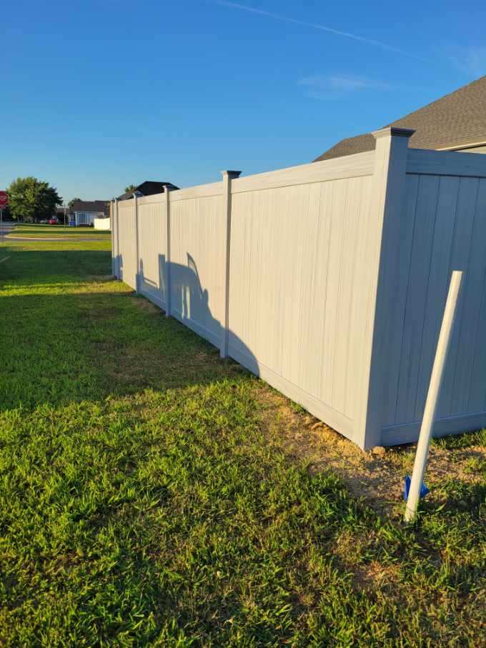 A white fence is sitting in the middle of a lush green field.