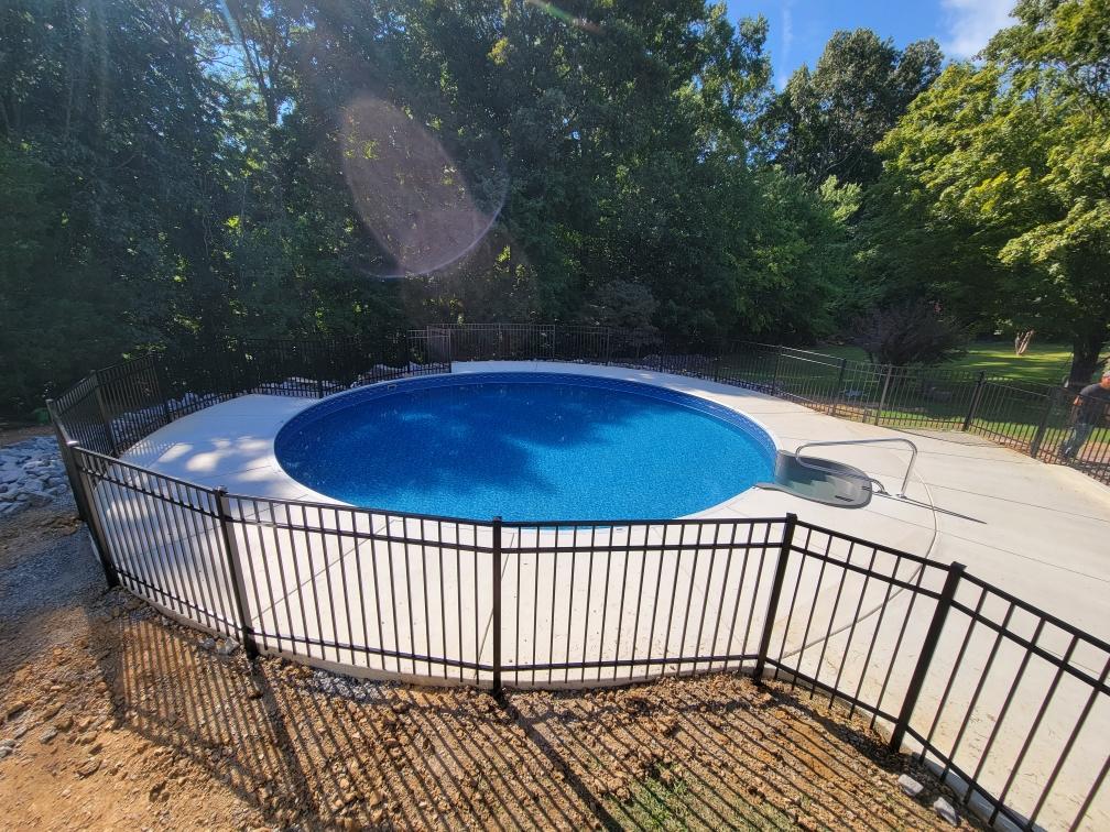 A large swimming pool surrounded by a fence and trees.