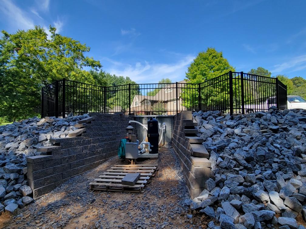 A pile of rocks is sitting on top of a pile of gravel next to a fence.