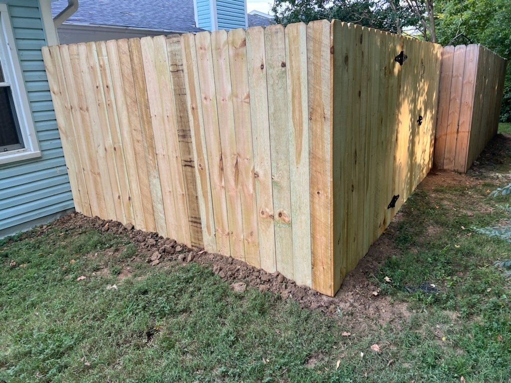 A wooden fence is sitting in the grass in front of a house.