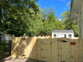 A wooden fence with a gate in front of a house.