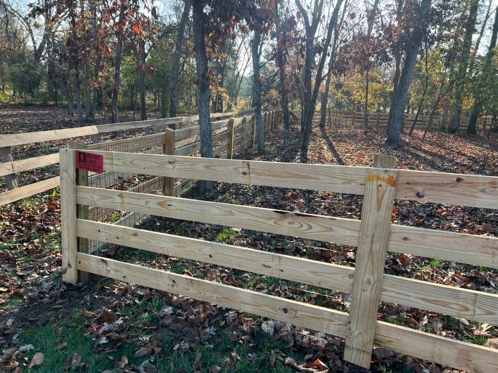 A wooden fence is in the middle of a forest.