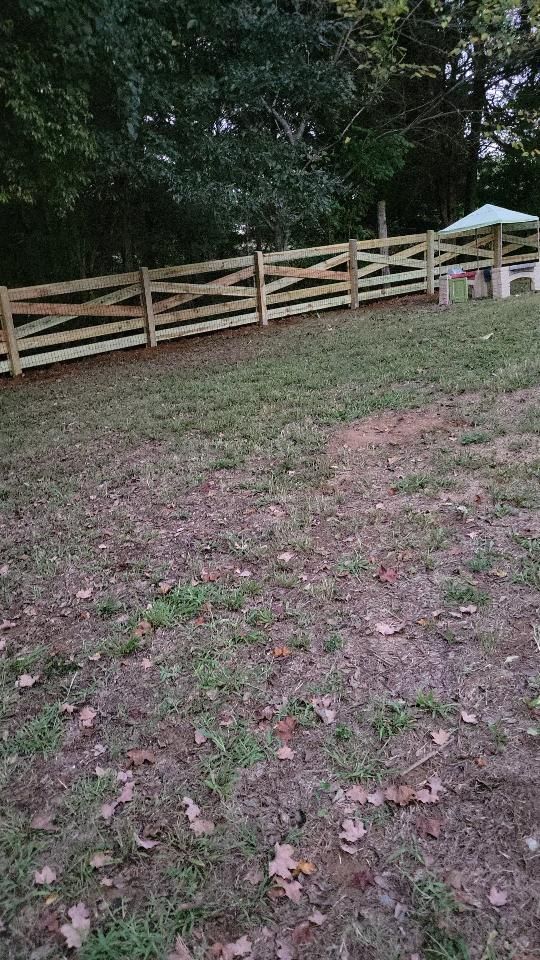 There is a wooden fence in the middle of a grassy field.