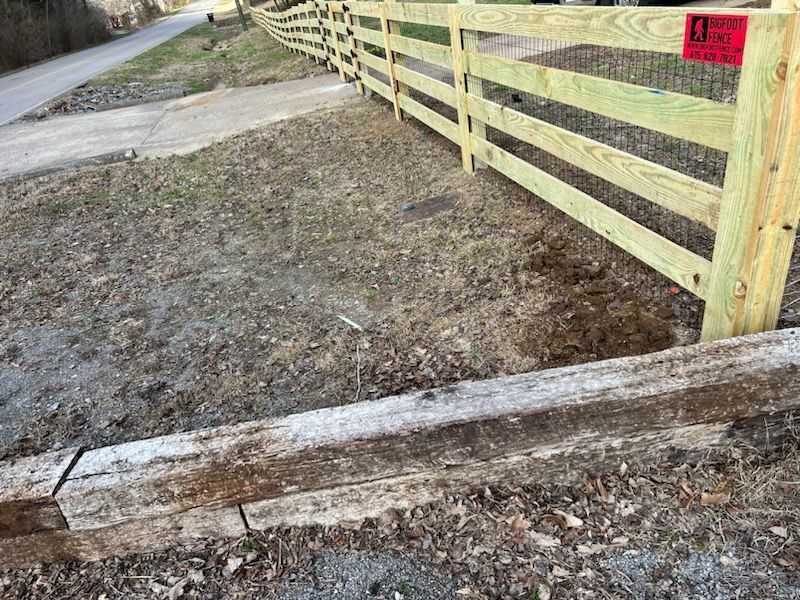 A wooden fence is sitting next to a wooden railroad track.