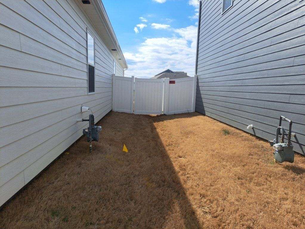 There is a white fence in the backyard of a house.