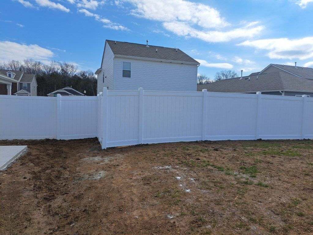 There is a white fence in the backyard of a house.