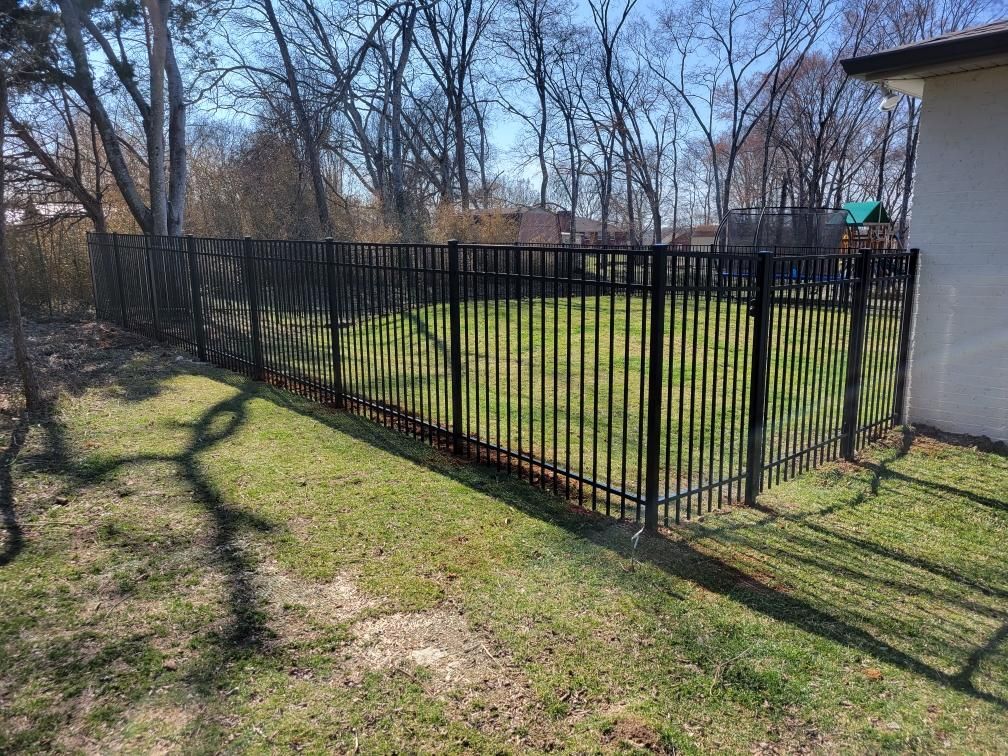A black metal fence surrounds a lush green yard.