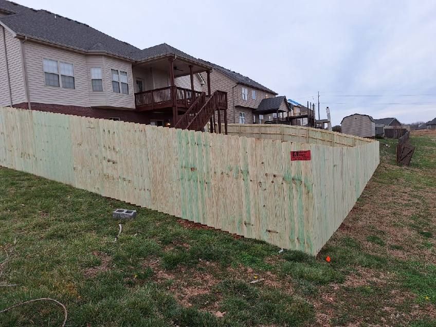 A wooden fence is sitting in the grass in front of a house.