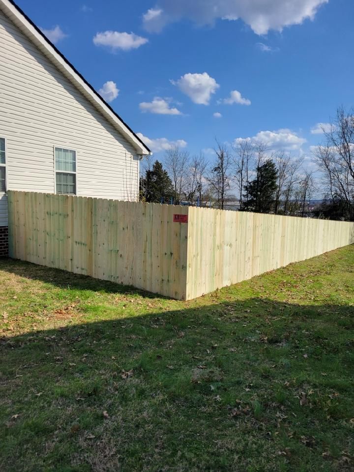 A wooden fence is in the backyard of a house.