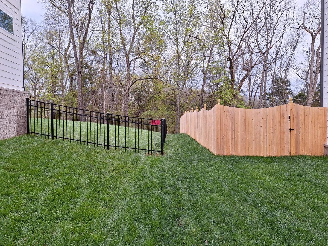 There is a wooden fence and a metal fence in the backyard.
