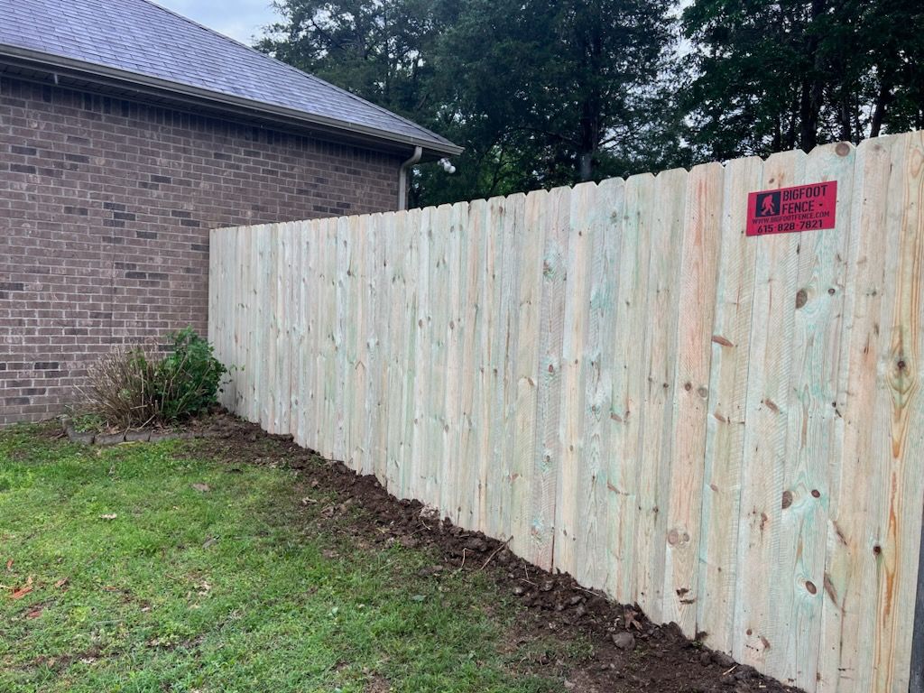A wooden fence is sitting in front of a brick house.