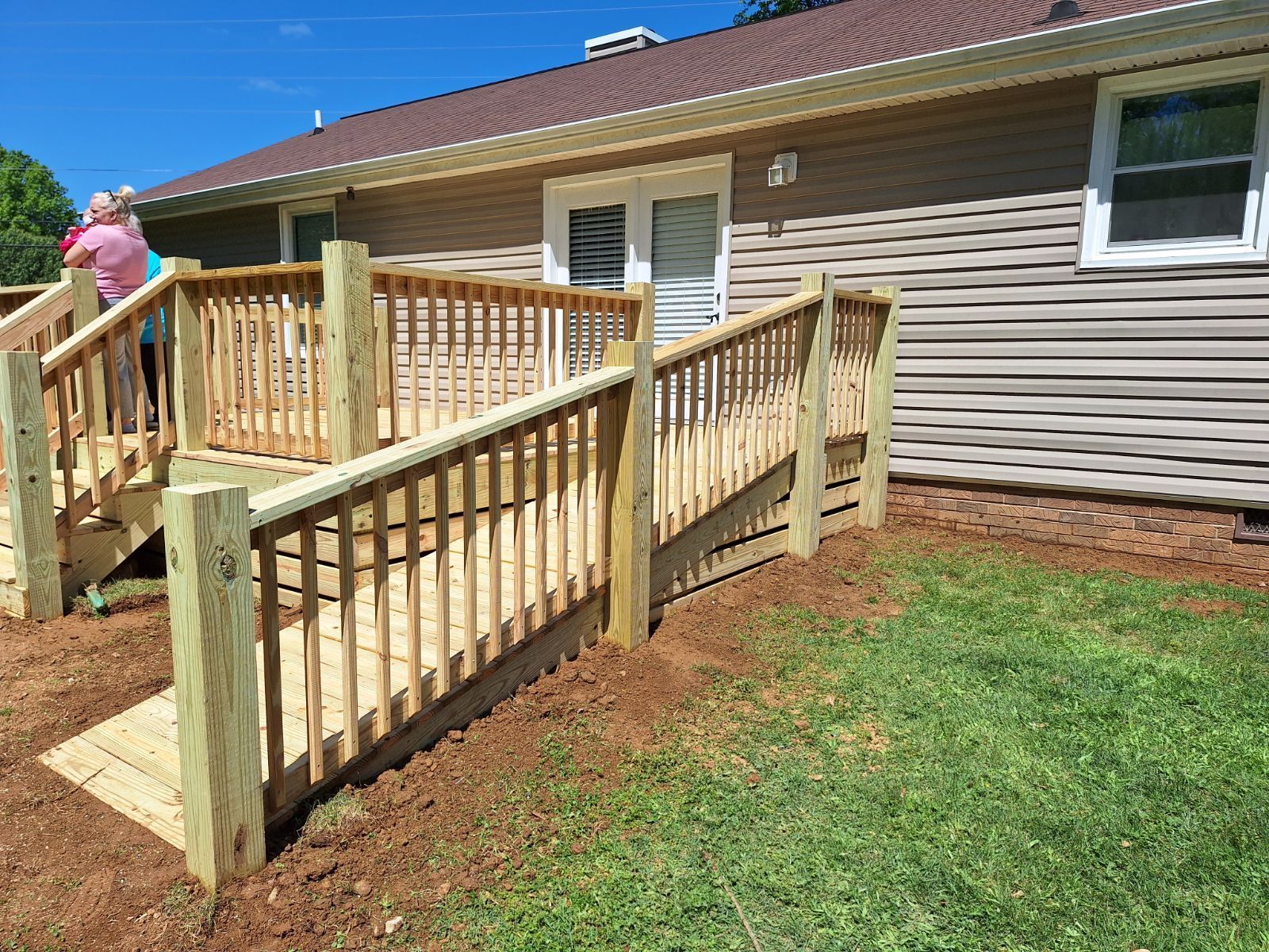 A woman is standing on a wooden deck next to a house.