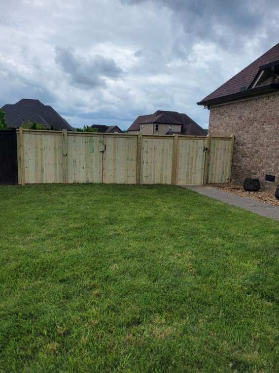 A wooden fence is in the backyard of a house.