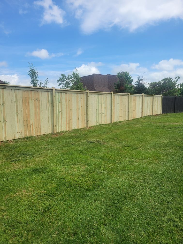 A wooden fence is in the middle of a lush green field.