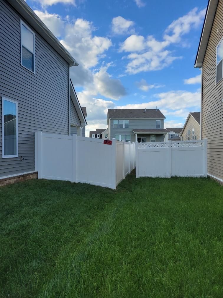 There is a white fence in the backyard of a house.