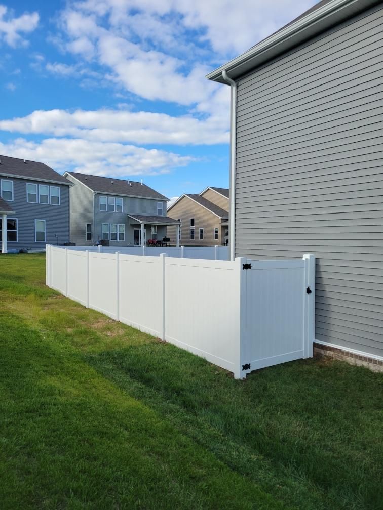 There is a white fence in the backyard of a house.
