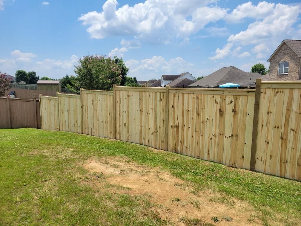 A wooden fence is in the backyard of a house.