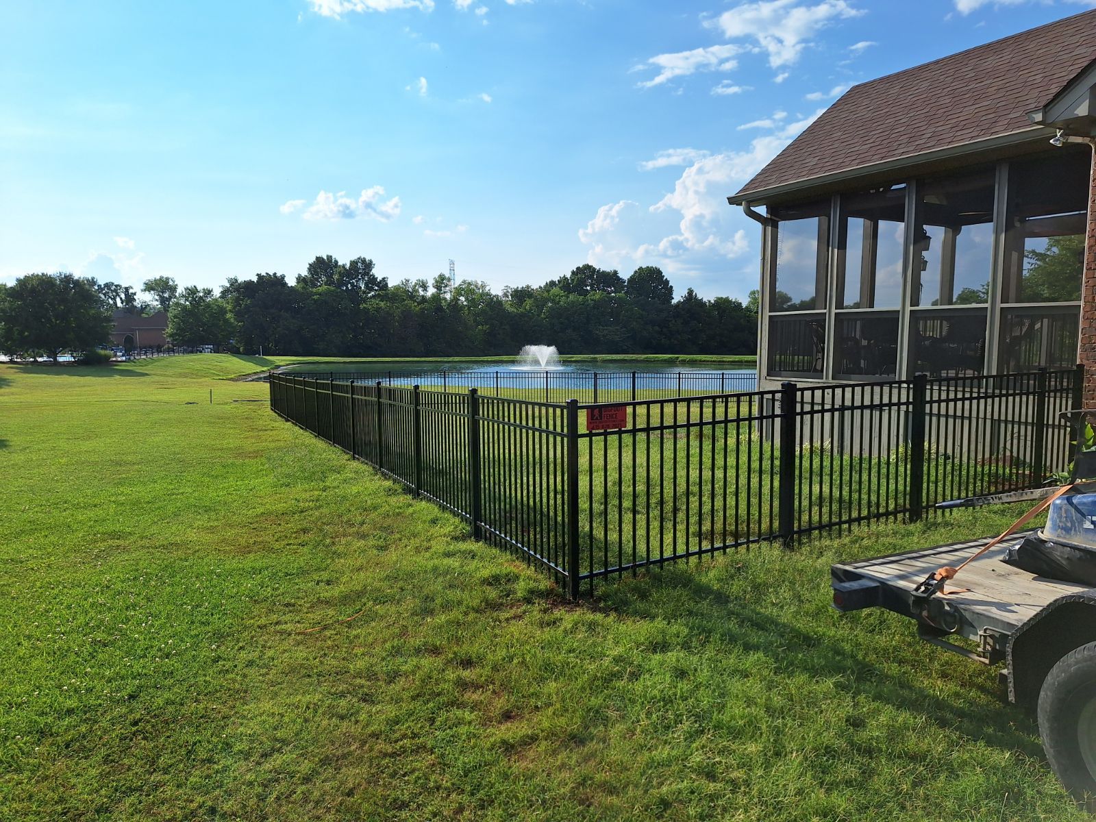 A metal fence surrounds a swimming pool in front of a house.
