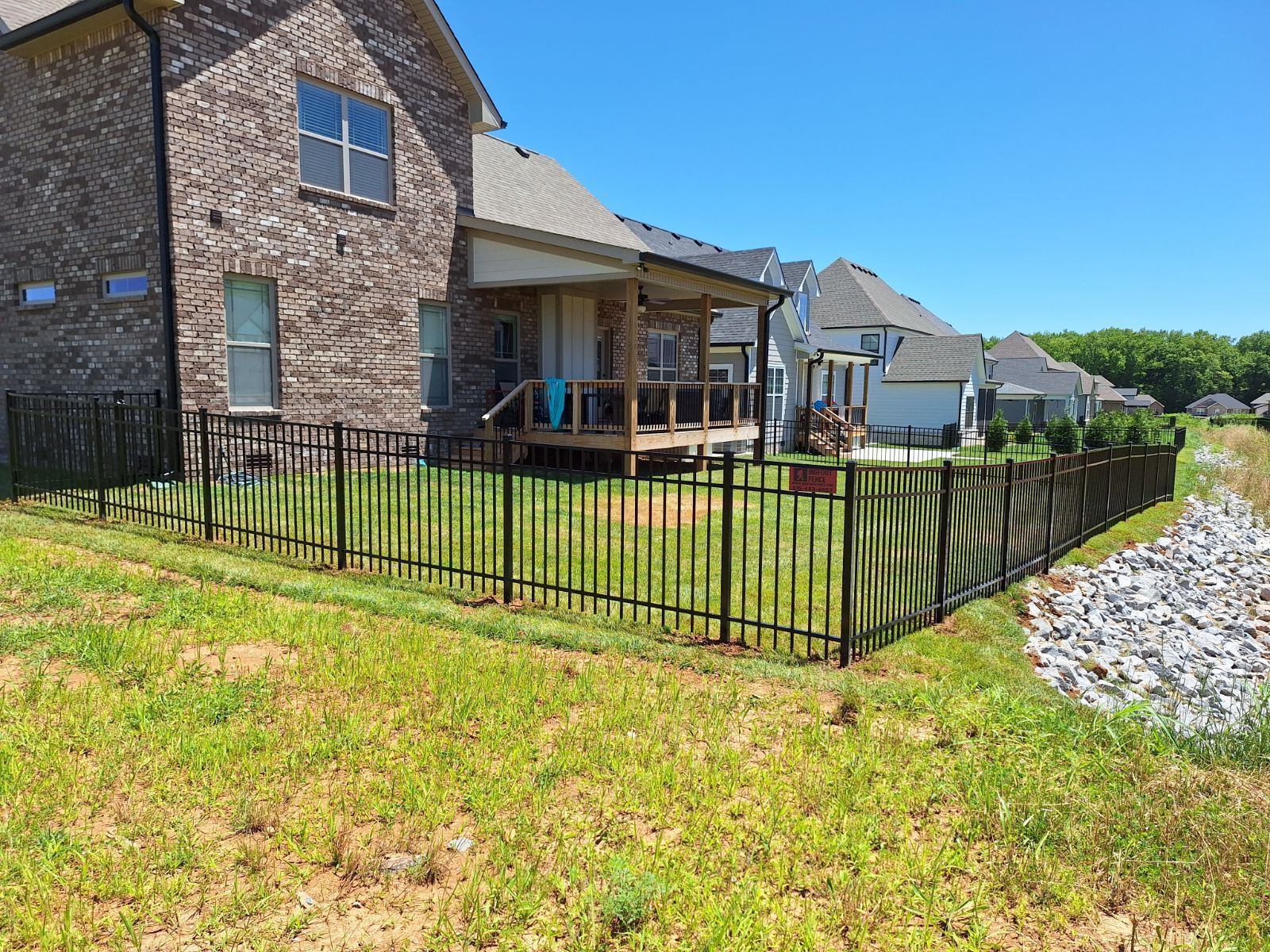 A house with a porch and a fence in front of it.