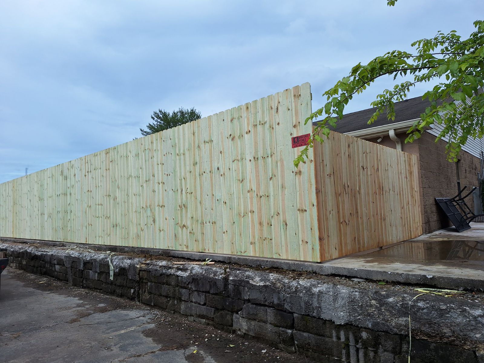 A large wooden fence is surrounding a stone wall.