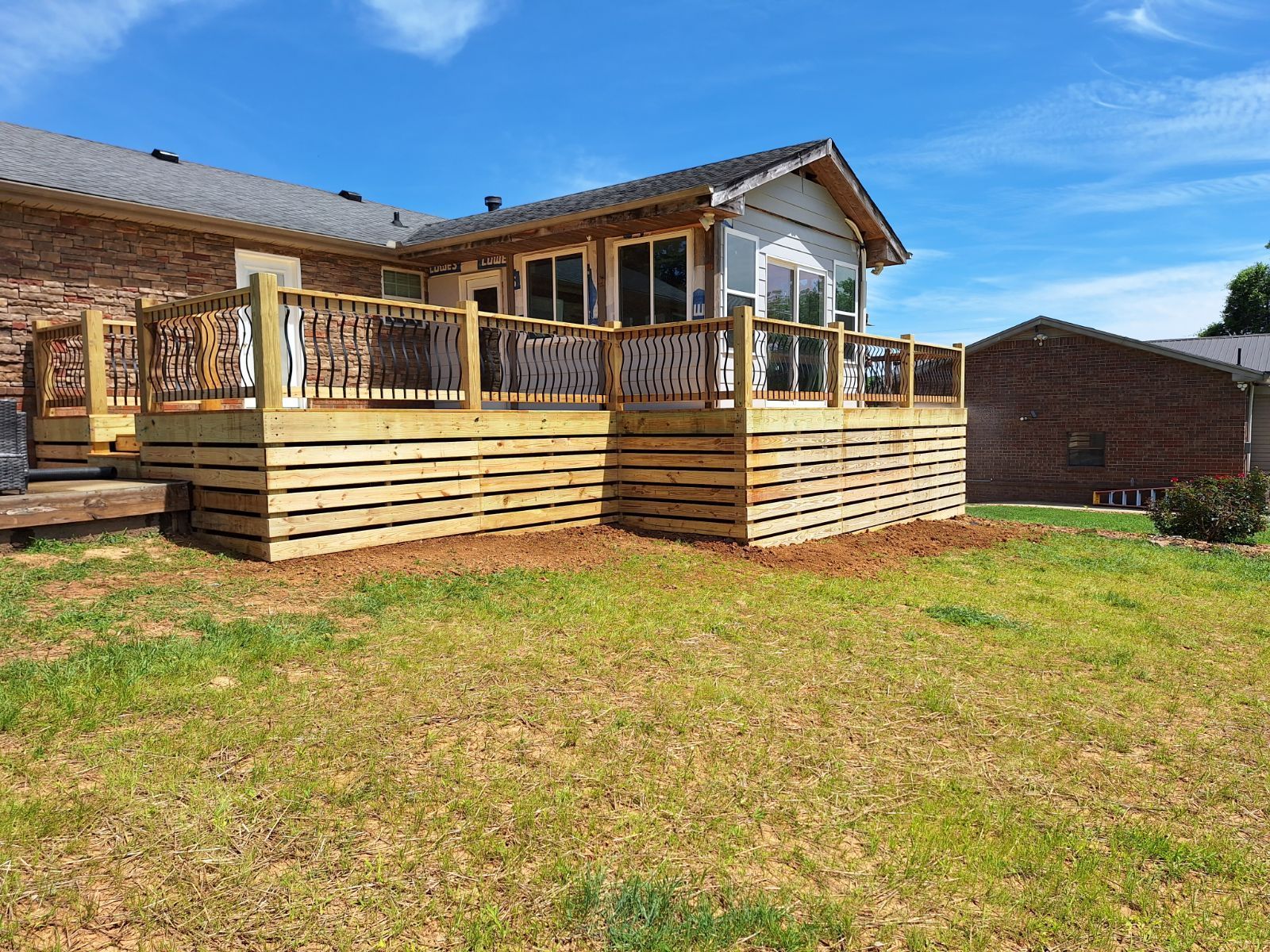 A large wooden deck is in the backyard of a house.