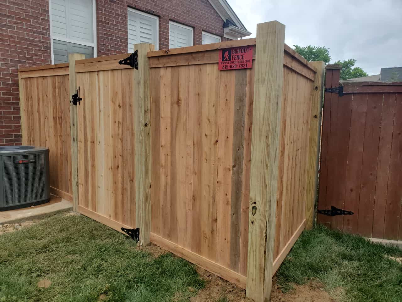A wooden fence with a gate is in the backyard of a house.