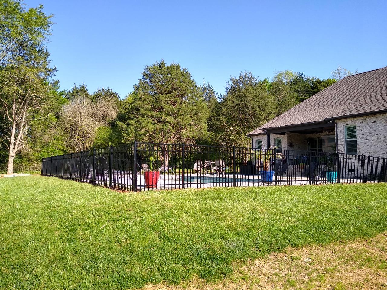 A house with a fence around it and a pool in the backyard.