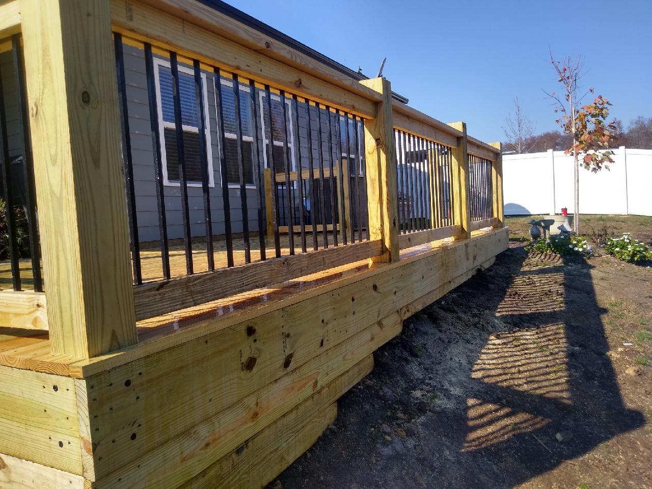 A wooden deck with a metal railing in front of a house.