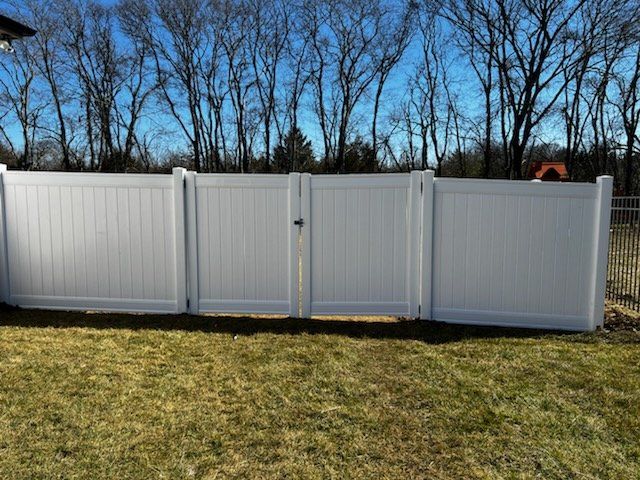 A white vinyl fence with a gate in the backyard.