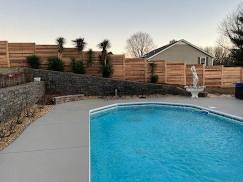 A large swimming pool surrounded by a wooden fence in a backyard.