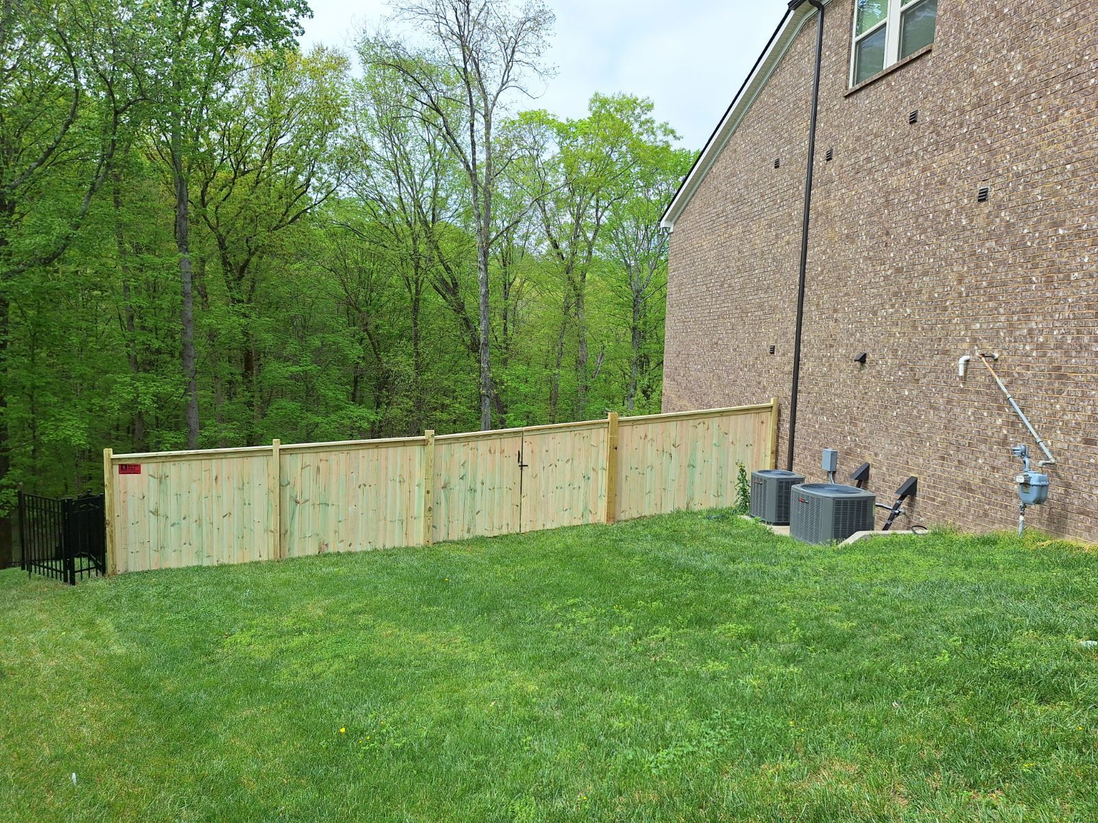There is a wooden fence in the backyard of a house.