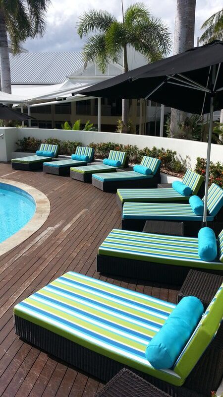 A Group Of Lounge Chairs And Umbrellas Next To A Pool — Stitch Master in Manunda, QLD