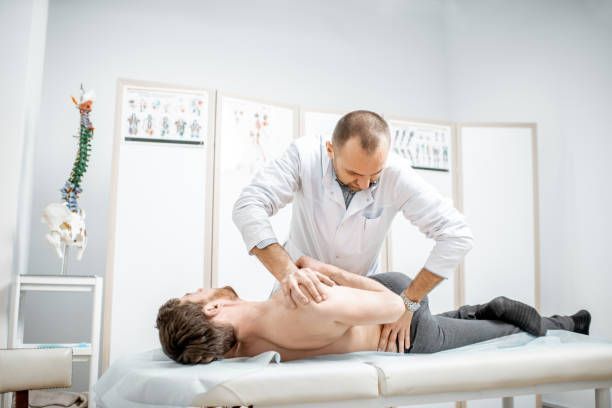 A practitioner performs a manual therapy or chiropractic adjustment on a person lying on a clinical examination table.